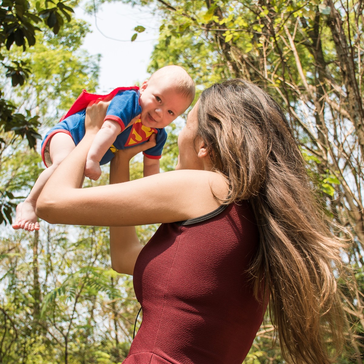 Women lifting a baby in a super man costume